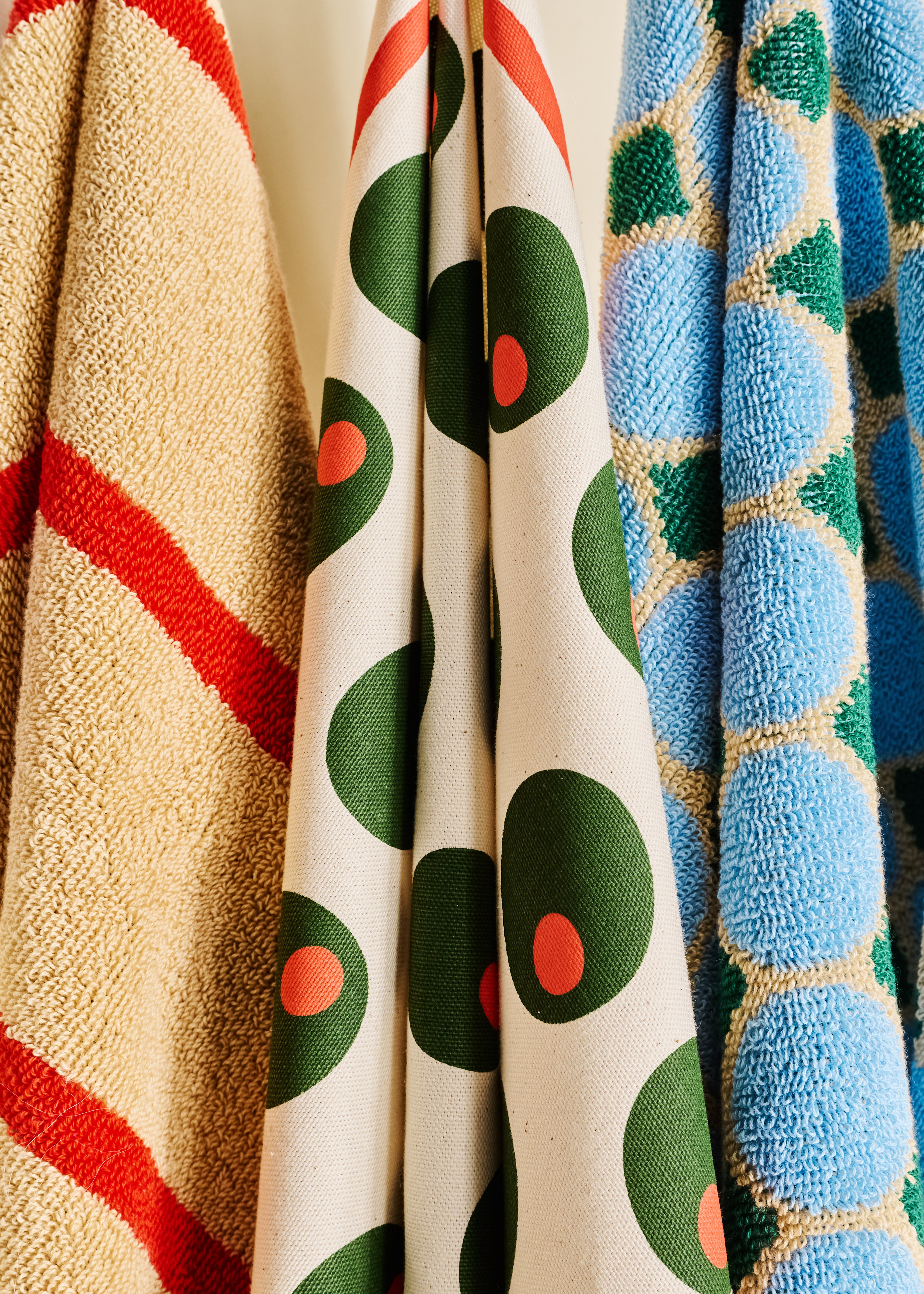 Three colorful towels with different patterns on a neutral background
