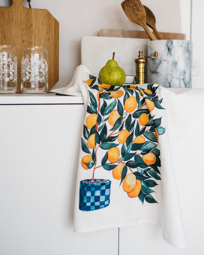 white tea towel with watercolor orange tree in checkered blue pot